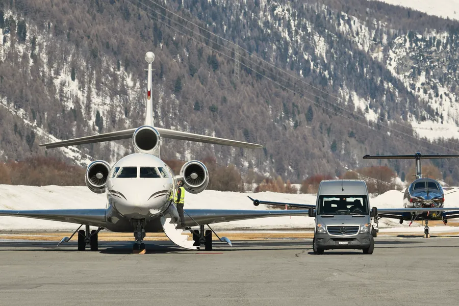 A private jet and a Mercedes van on a snowy Alpine airfield