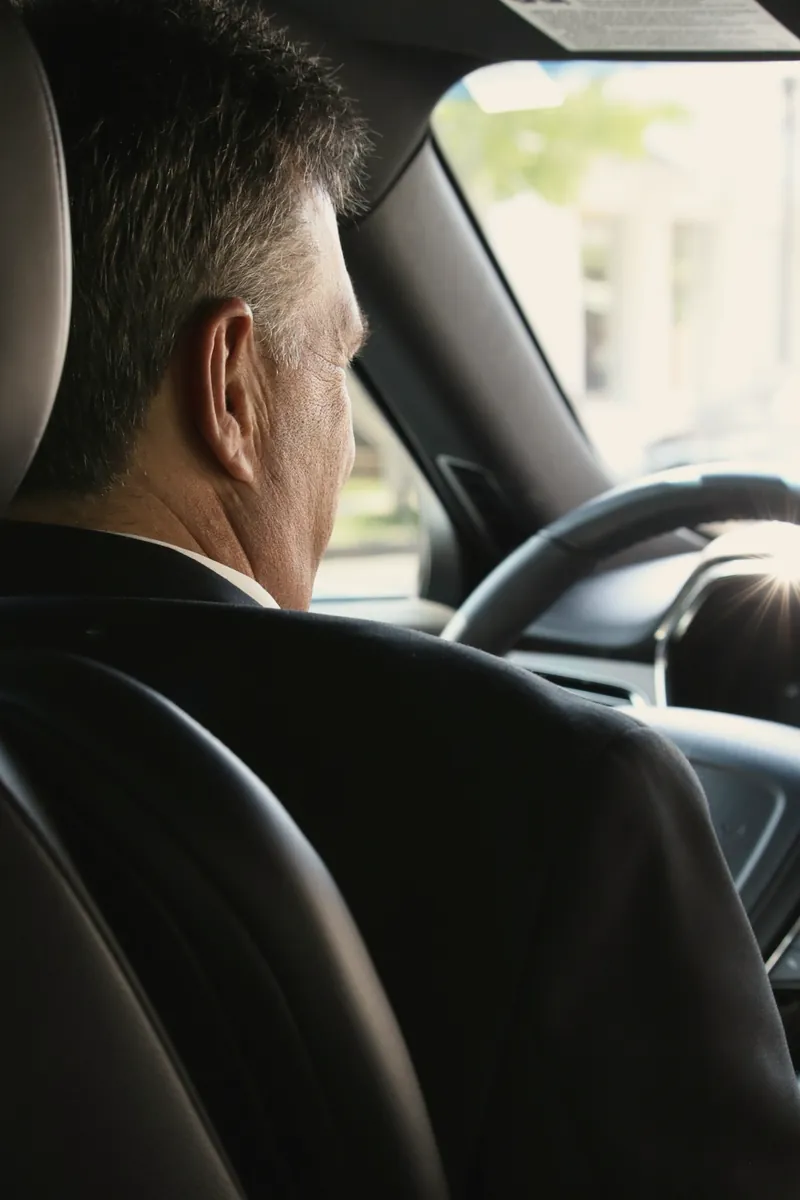 A chauffeur in a dark suit at the wheel