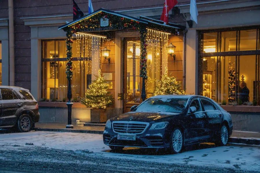 A black Mercedes S-Class waiting outside a hotel in the snow